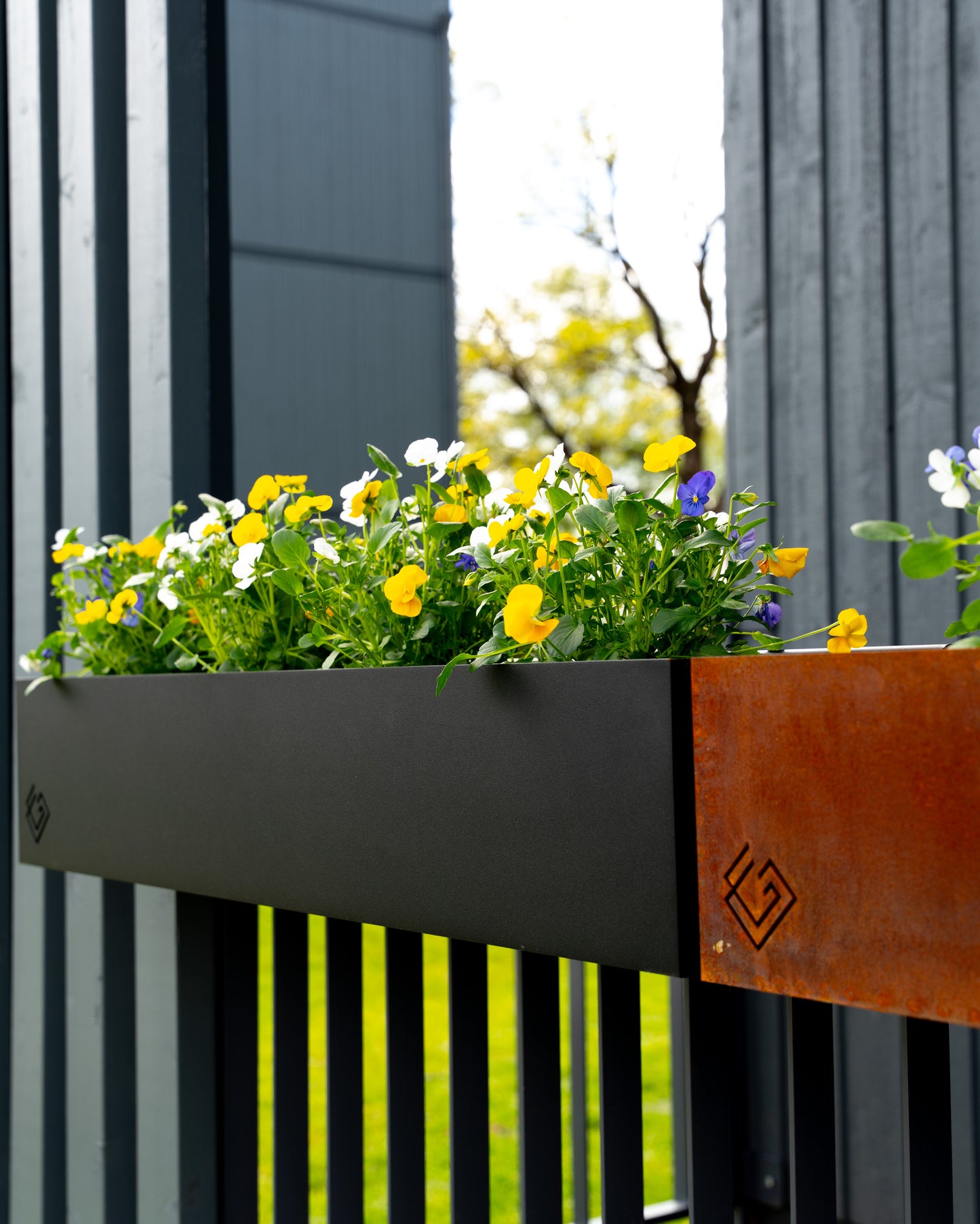 Melna metāla puķu kaste ar puķēm